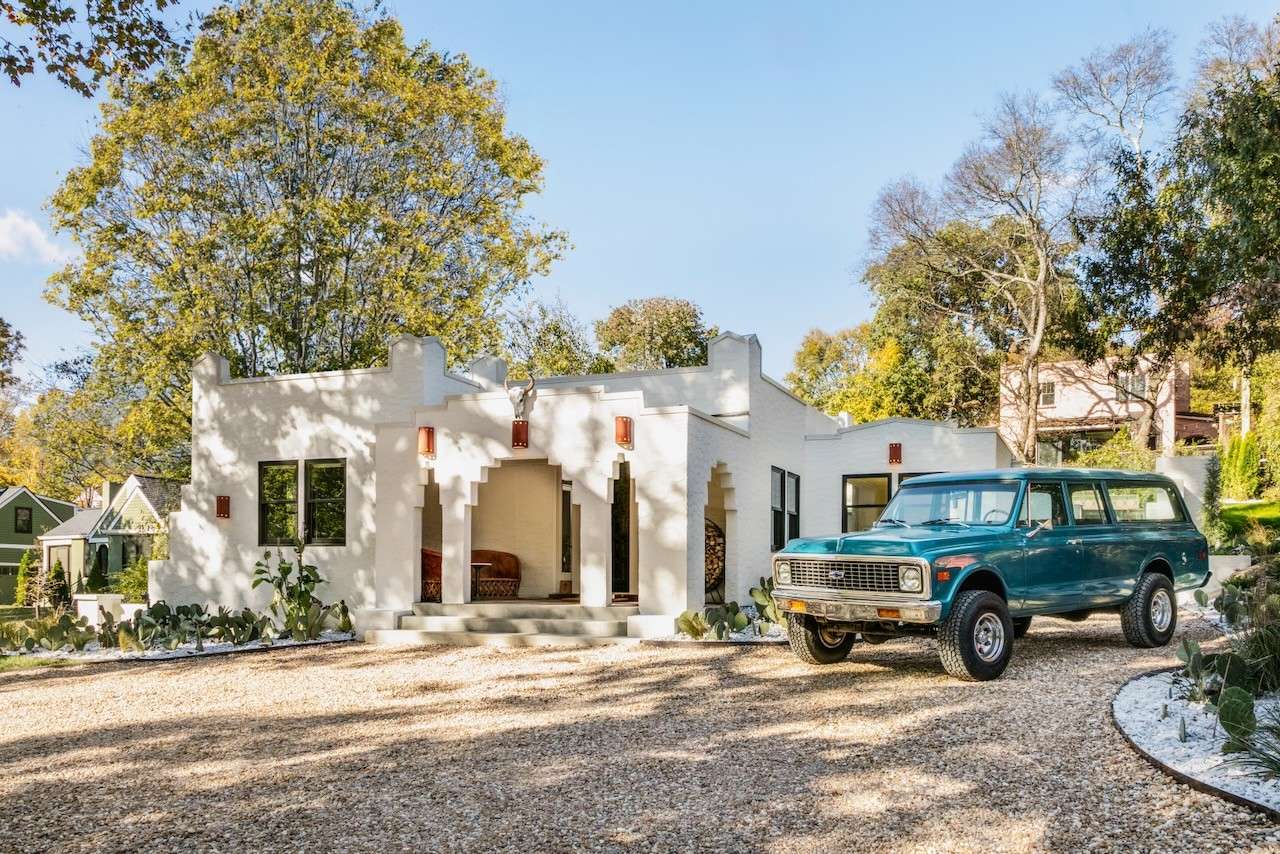 White Spanish-style home with a decorative entry arch and vintage Chevrolet parked outside