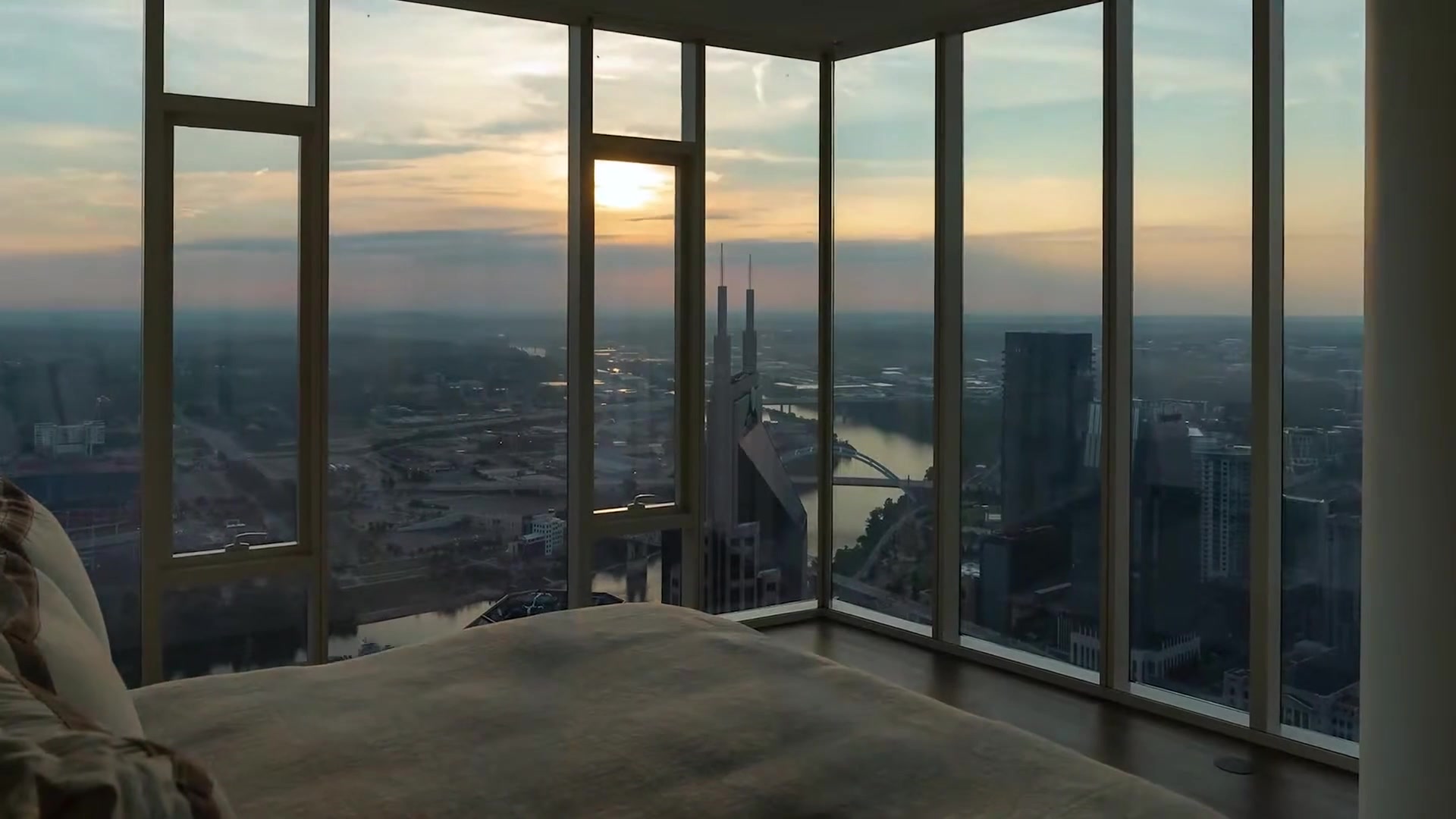 Nashville skyline at sunset through the floor-to-ceiling windows of a high-rise bedroom