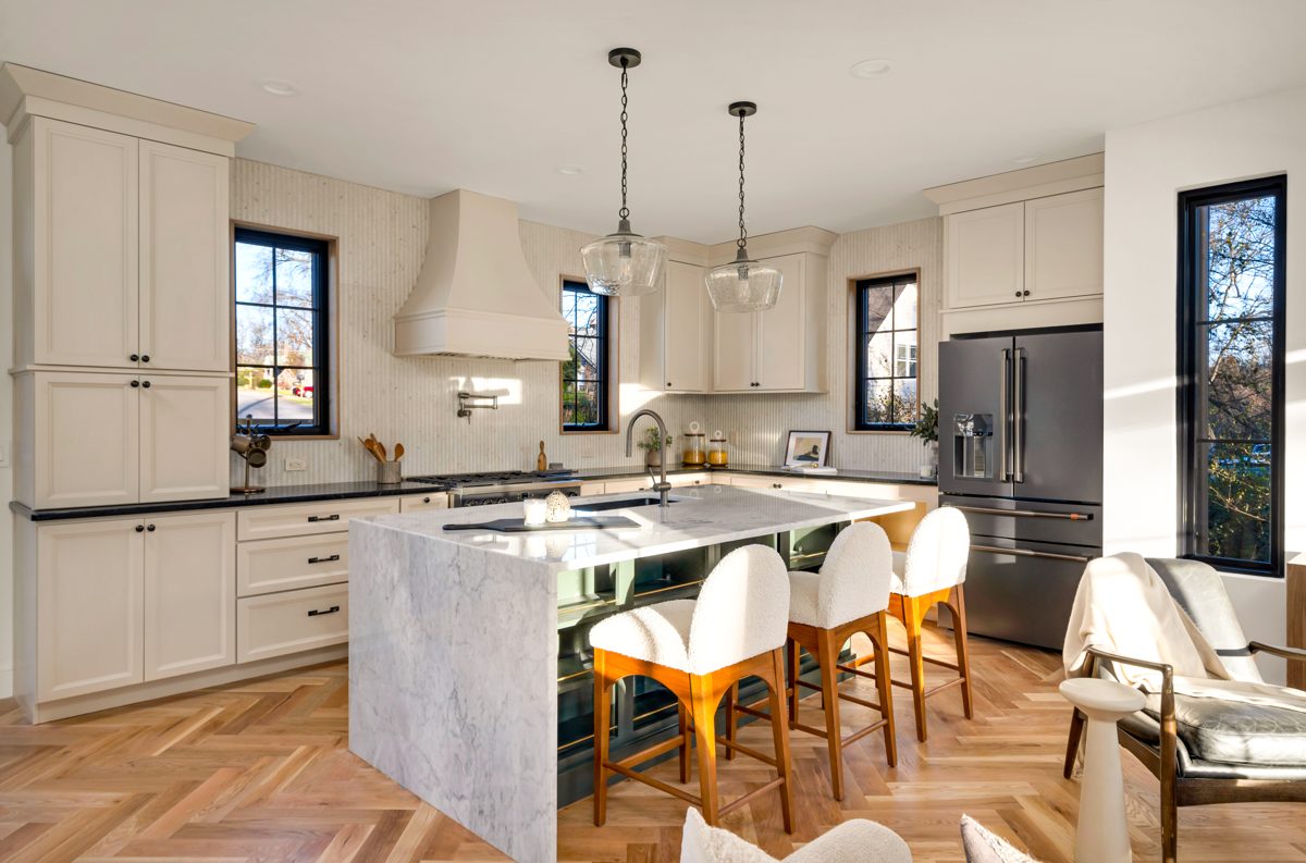 Kitchen with a marble island, pendant lights and herringbone floors